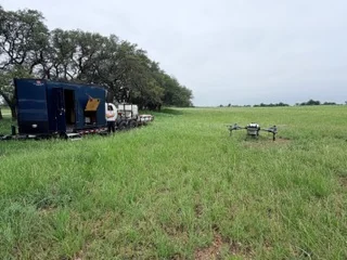 Centex Agri-Drone navy spray trailer in a pasture with a spray drone ready to fly