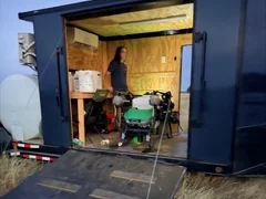 Inside the open Centex spray trailer on a job, with drones and batteries ready