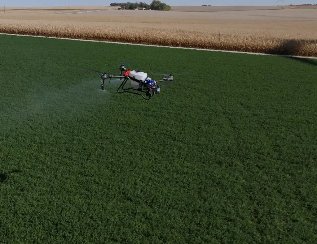 Revolution I-19 agricultural spray drone spraying a green alfalfa field