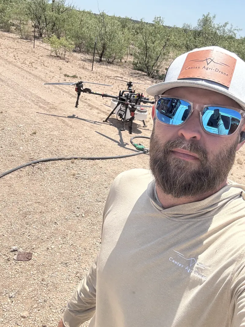 Josh Shahan, owner of Centex Agri-Drone, in the field with a spray drone