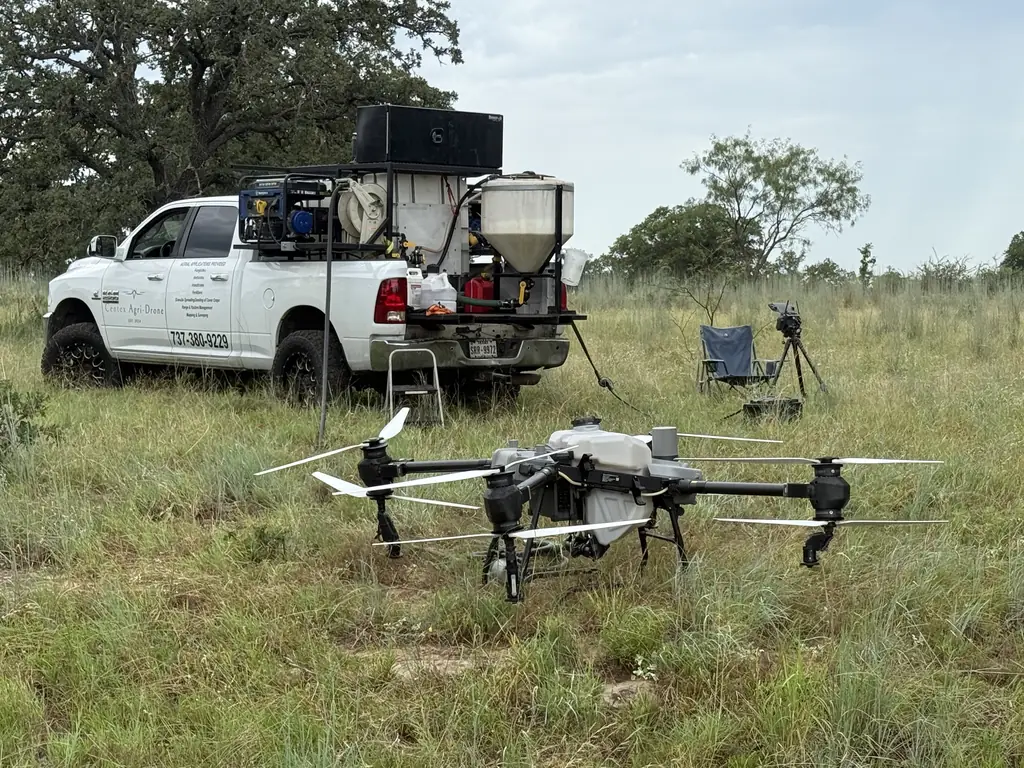 DJI Agras T50 in a pasture in front of the Centex Agri-Drone truck and mixing rig
